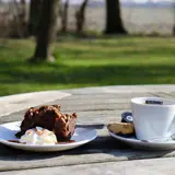 Buiten genieten van een gebakje en een hete koffie ernaast