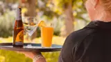 Een serveerster met een biertje en een jus d'orange die klanten gaat bedienen